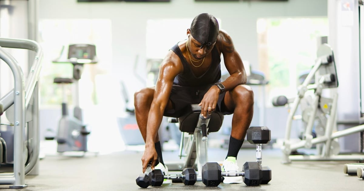 Athlete resting between sets in a gym, checking their watch to time recovery period