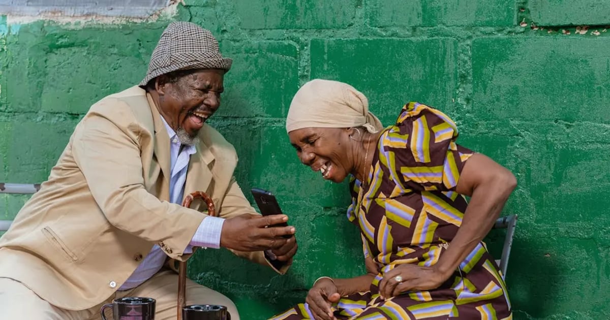 Elderly couple happily using a smartphone together