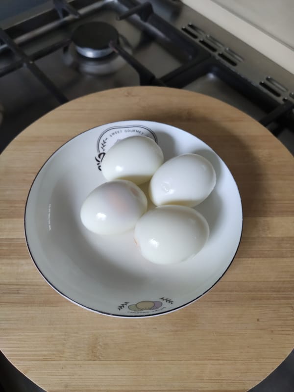 Four peeled boiled kienyeji eggs on a patterned ceramic saucer