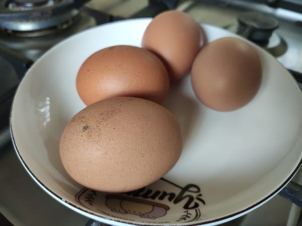 Whole brown chicken eggs on a white plate