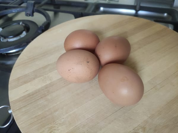 Whole brown chicken eggs on a wooden cutting board