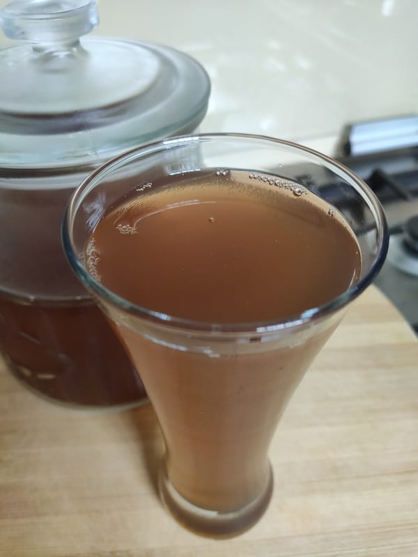 Homemade kombucha tea poured into a glass, showing its amber colour and light carbonation