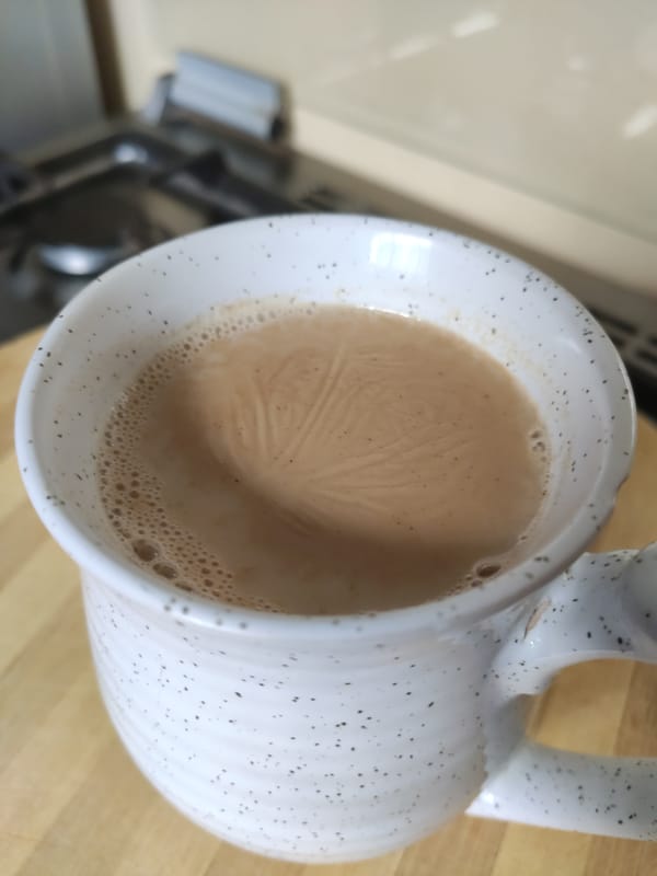 Close-up of homemade spiced Kenyan chai showing its milky surface foam
