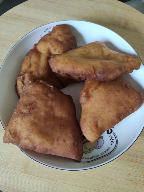 Homemade mandazi arranged on a plate, freshly fried and golden