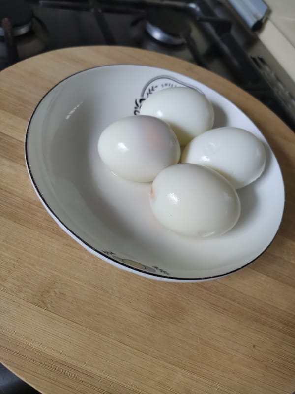 Mayai ya kuchemsha - peeled kienyeji boiled eggs in a ceramic saucer on a wooden board