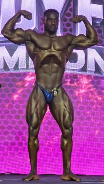 Dennis Junior Litali performing a front double biceps pose at Body Fuel Championship 2026
