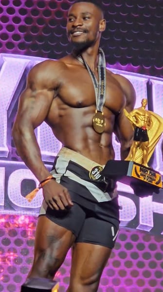 George Kajula holding a physique trophy at Body Fuel Championship 2026