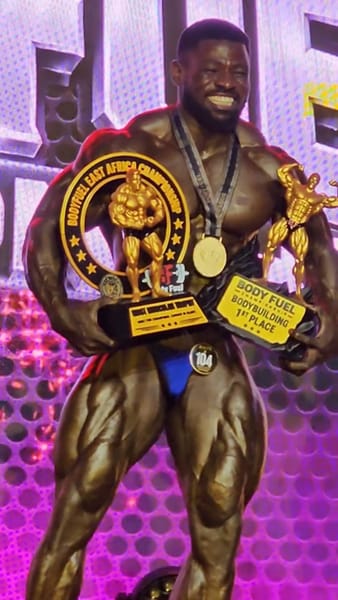 King Cobra holding bodybuilding trophies and wearing his medal at Body Fuel Championship 2026
