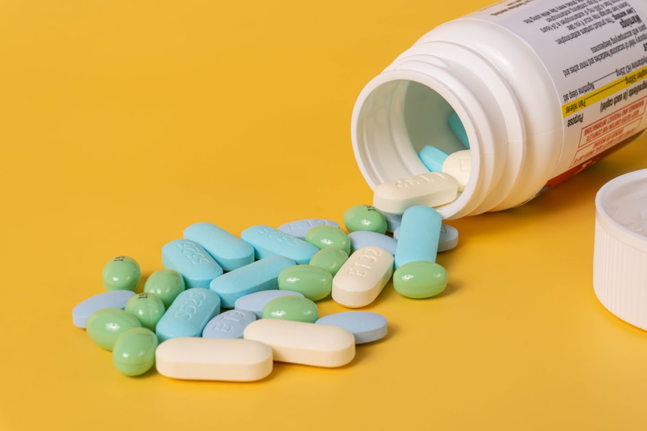 Mixed pills spilling out of a pill bottle.